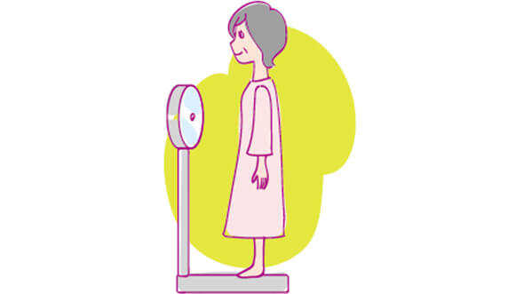 イメージ：体重計に乗り体重を計る女性